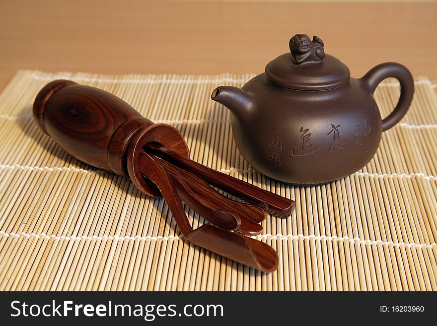 Brown chinese teapot and tea tools on a bamboo mat