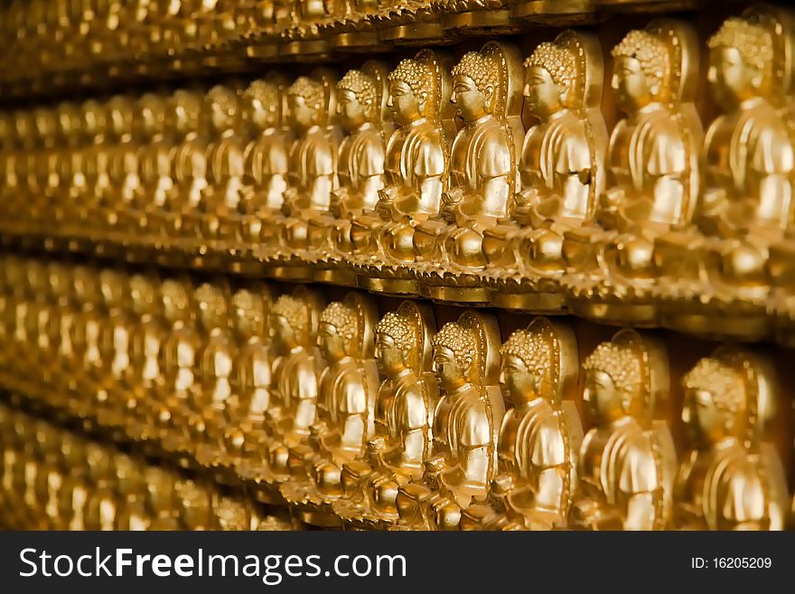 Many golden buddha image on wood wall perspective