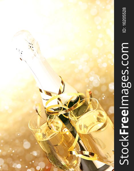 Studio photo of champagne glasses with bottle and golden decoration on background. Studio photo of champagne glasses with bottle and golden decoration on background