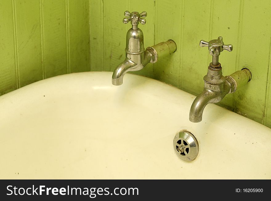 Taps in a bathroom with  green walls