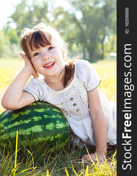Beautiful little girl lying in meadow, leaning against a watermelon and dreams. Beautiful little girl lying in meadow, leaning against a watermelon and dreams