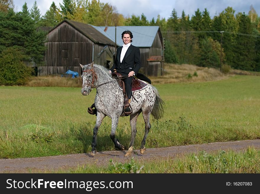 A man in tuxedo riding appaloosa mare with western tack. A man in tuxedo riding appaloosa mare with western tack