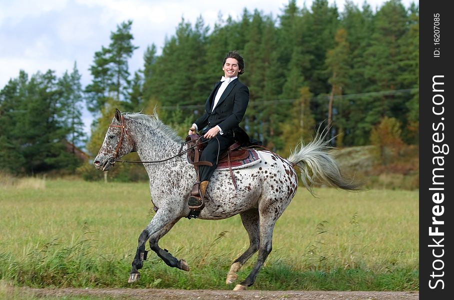 A man in tuxedo riding appaloosa mare with western tack. A man in tuxedo riding appaloosa mare with western tack