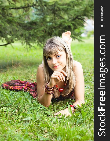 Cheerful young girl lying on the grass and smiling