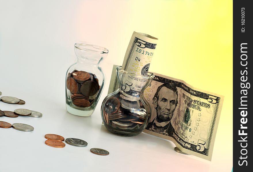 Coins in class jars and $5 bills with colorful background. Coins in class jars and $5 bills with colorful background