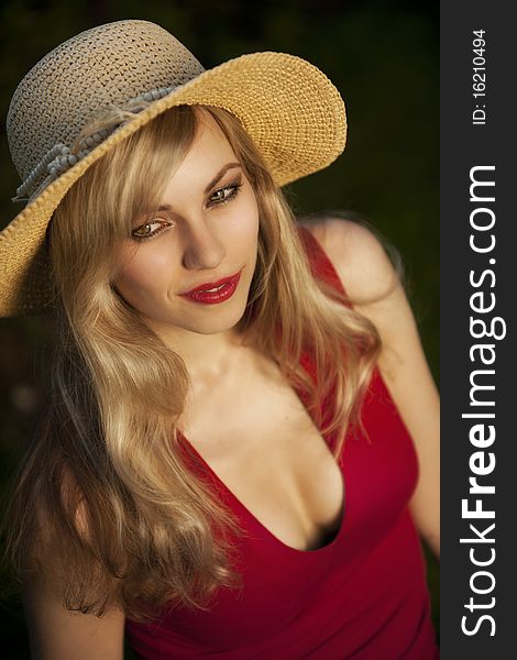 High angle view of fashionable young blond woman with straw hat, black background.