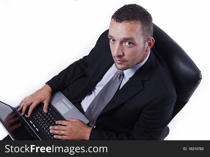 Successful businessman in his chair, with laptop, working and looking at camera, isolated on white. Successful businessman in his chair, with laptop, working and looking at camera, isolated on white