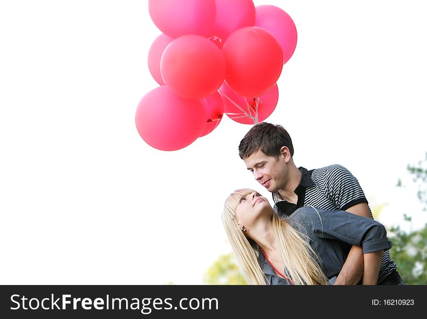 Young loving couple with red balloons over white