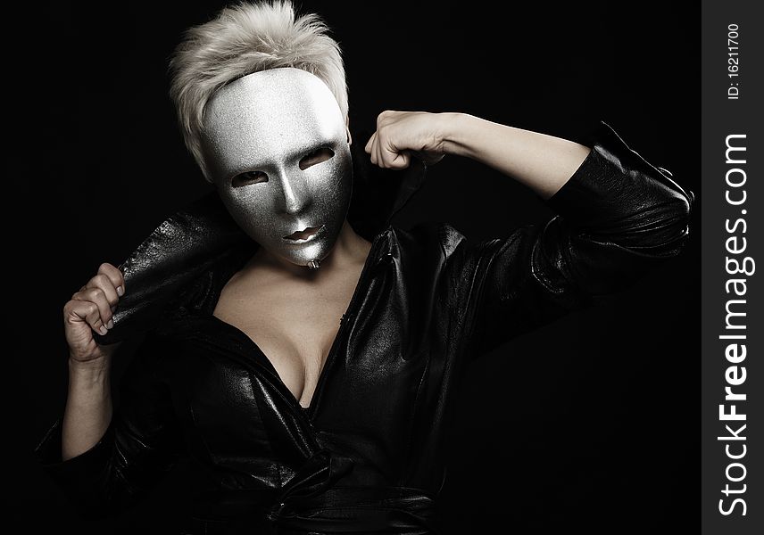Gloomy woman in silver mask posing on a black background