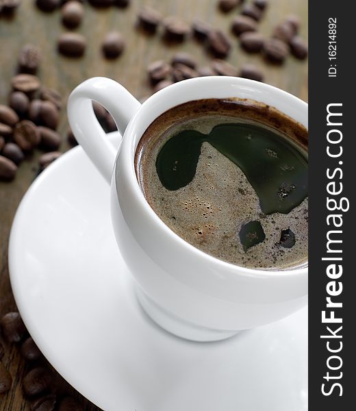 Cup of coffee with coffee beans on background