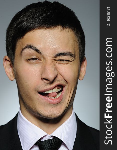 Portrait of funny business man in formal suit and black tie . expressions on gray background