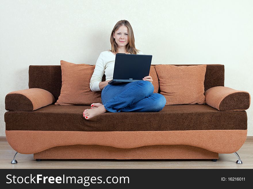 Young beatiful woman with laptop on the sofa