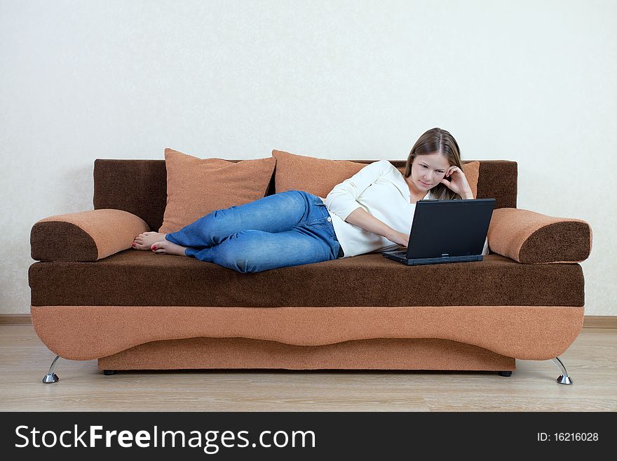 Young beatiful woman with laptop on the sofa