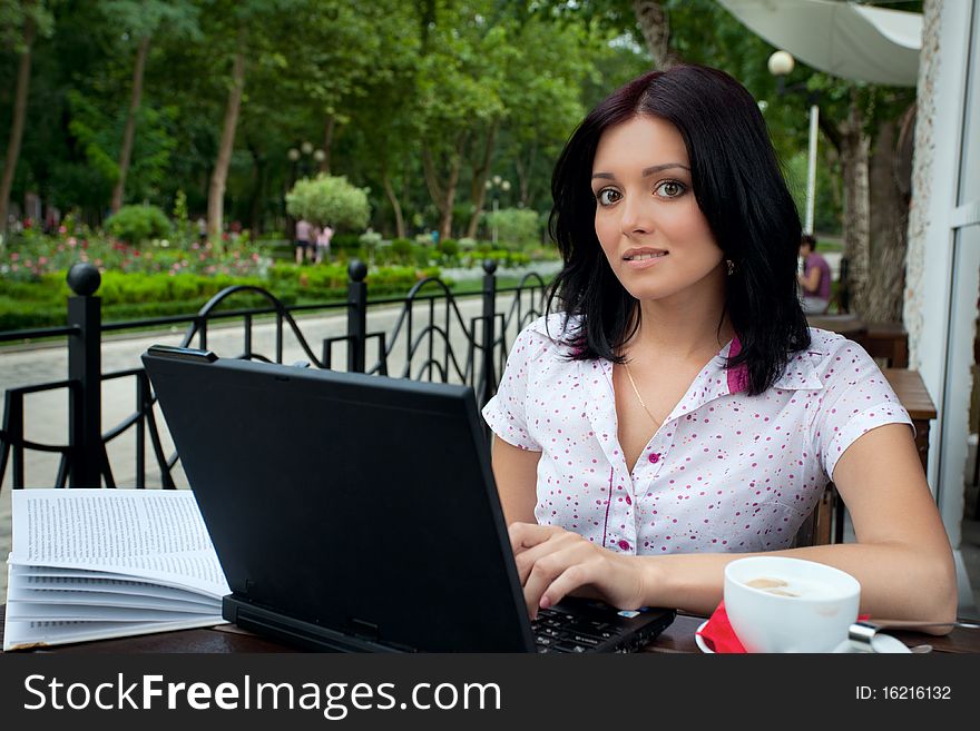 Young beautiful student girl with laptop and cup of coffee in cafe. Young beautiful student girl with laptop and cup of coffee in cafe