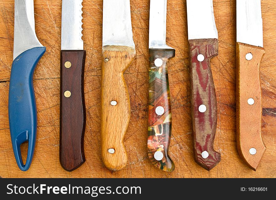 Several old, used knives on a cutting board. Several old, used knives on a cutting board