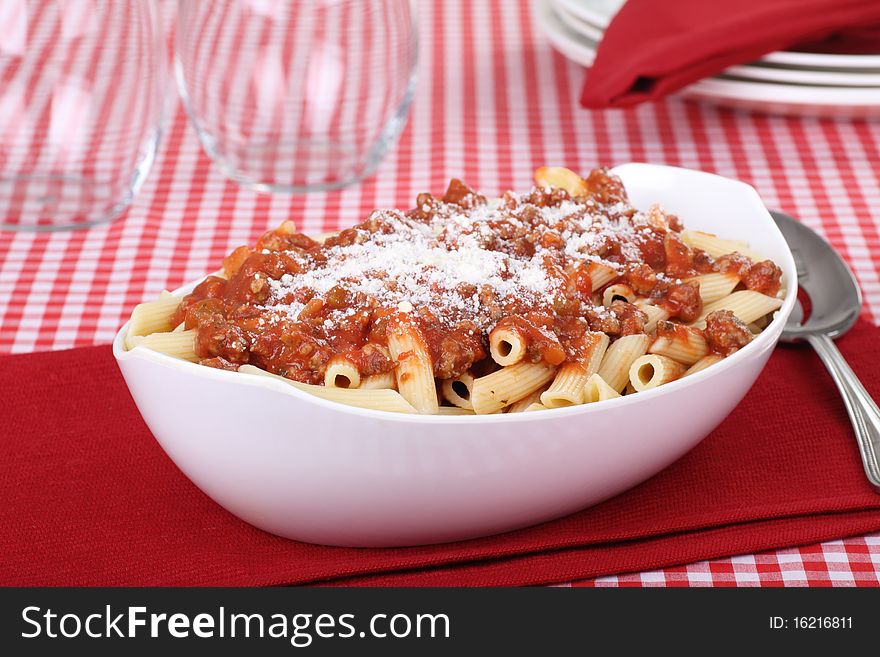 Penne pasta topped with tomato meat sauce and parmesan cheese in a serving bowl. Penne pasta topped with tomato meat sauce and parmesan cheese in a serving bowl