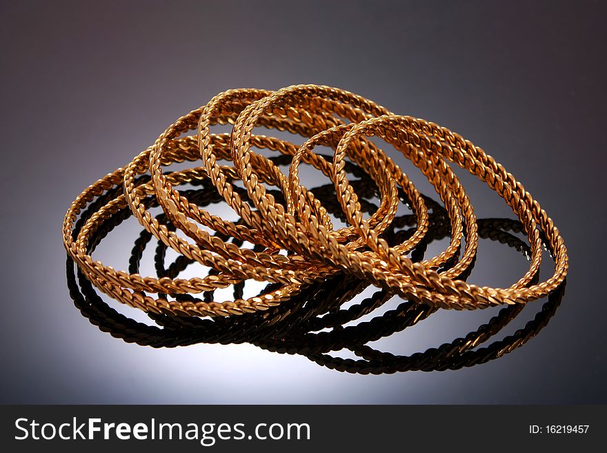 Gold bracelets isolated on black background with reflection