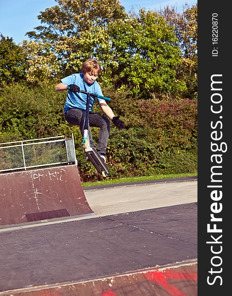 Young boy going airborne with his scooter at the skate park