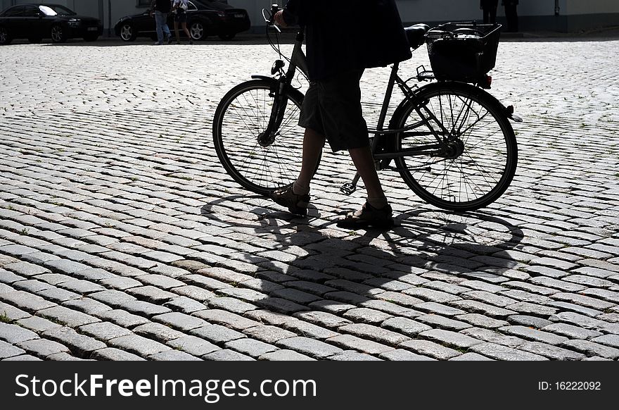 Man walking his bicycle on an old cobblestone road