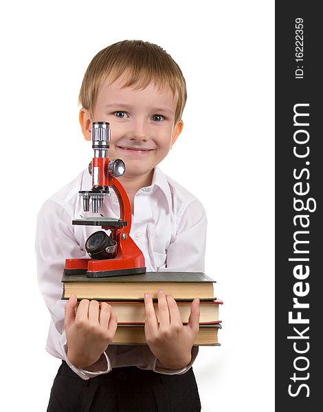 Happy boy with a stack of books and microscope on a white background