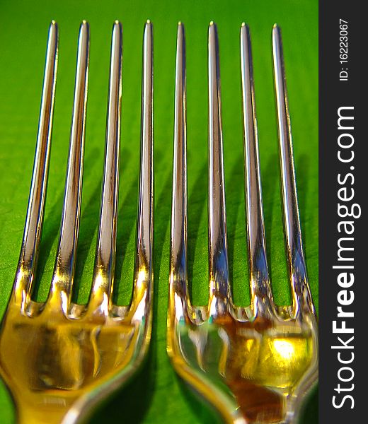 Long shiny forks on green table cloth