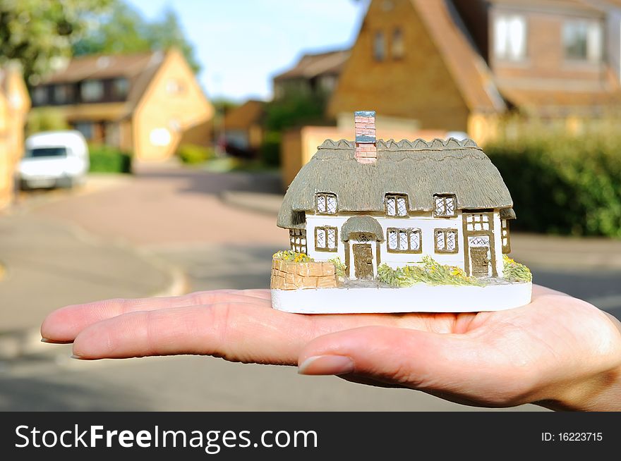 Small house in womans hand, outdoor.