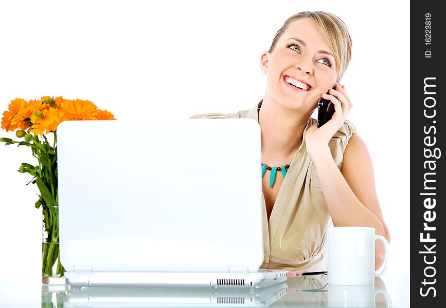 Beautiful happy female sitting behind desk with laptop, talking on the phone. Beautiful happy female sitting behind desk with laptop, talking on the phone