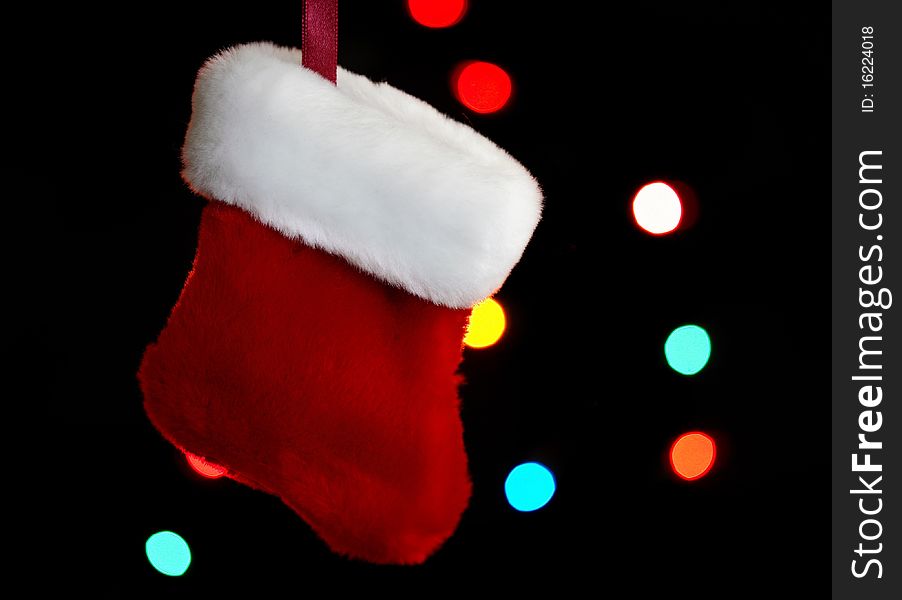 Very small sized holiday stocking hanging with lights in background.