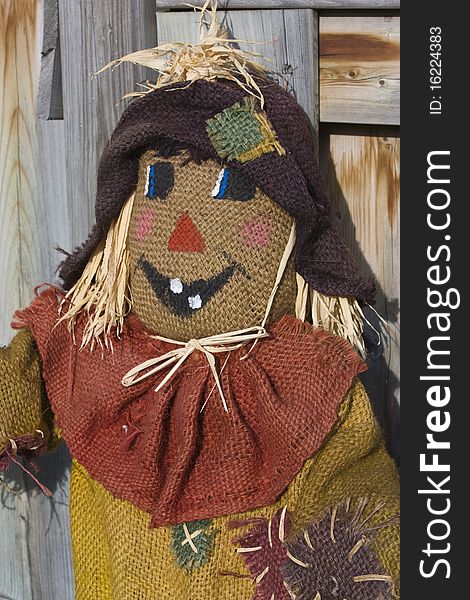 Closeup of scarecrow with a wooden fence in the background used as fall decoration. Closeup of scarecrow with a wooden fence in the background used as fall decoration