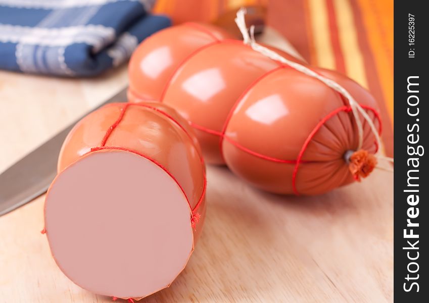 Boiled sausage, on a wooden cutting board.