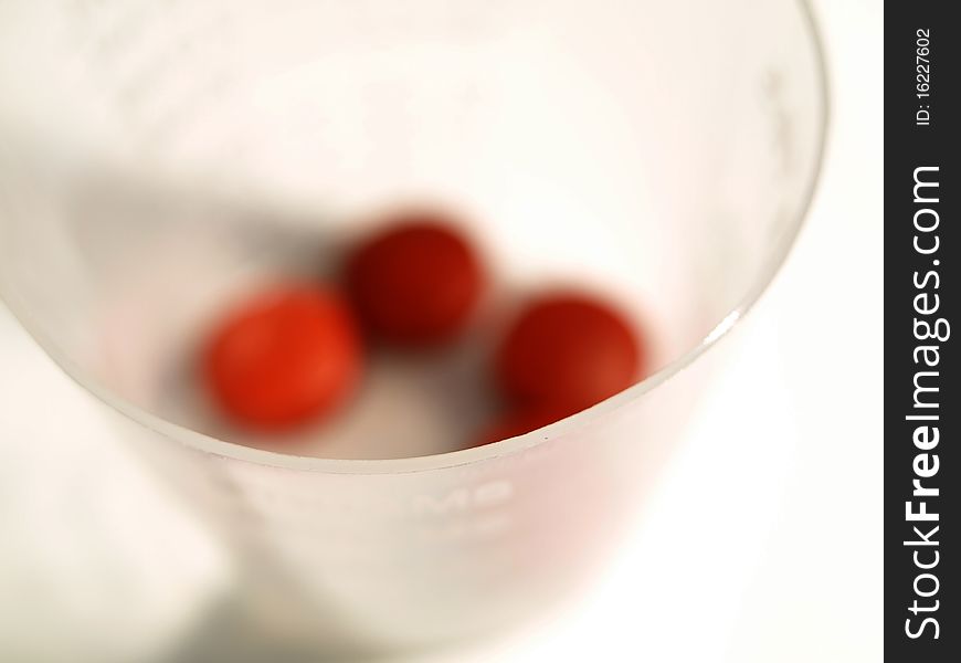 Close up shot of medicine cup with blurred red tablets
