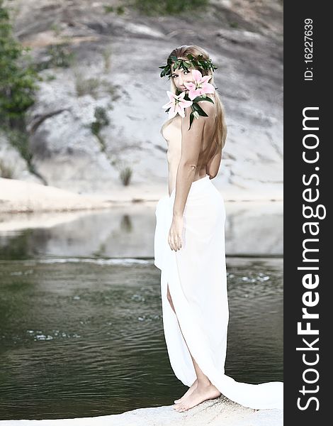 Beautiful woman as a forest nymph on the river