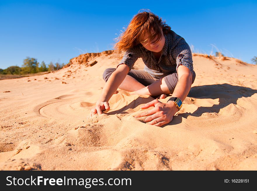 The girl sits on sand and enjoys the nature. The girl sits on sand and enjoys the nature