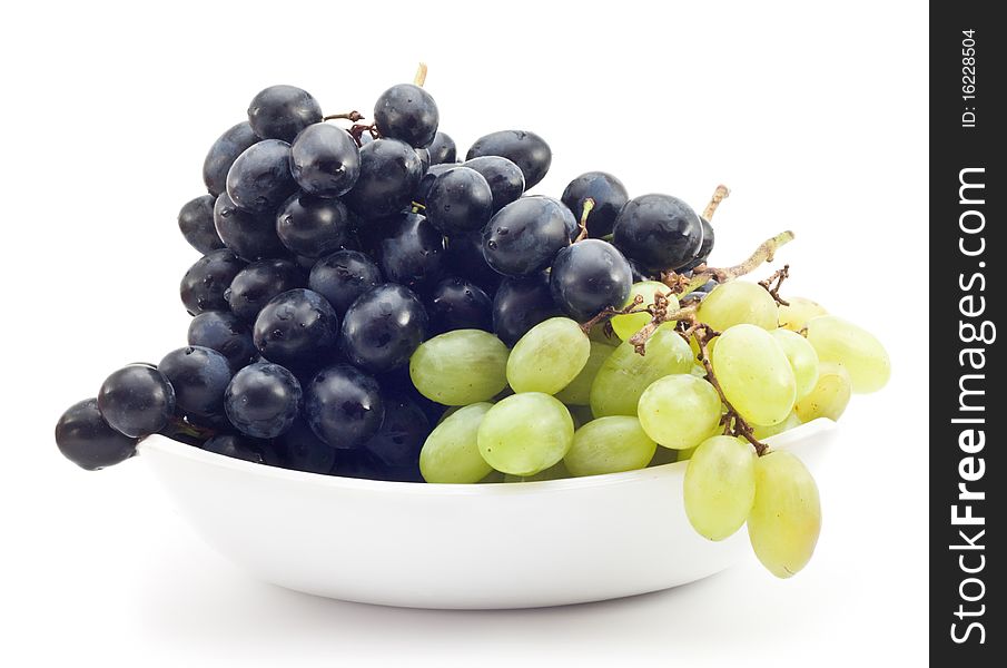 Branch of green and black grapes on a plate, white background