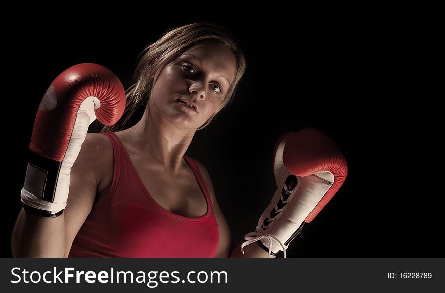 Young beautiful boxer girl over black background