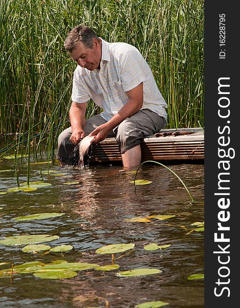 Happy senior man scaling fish