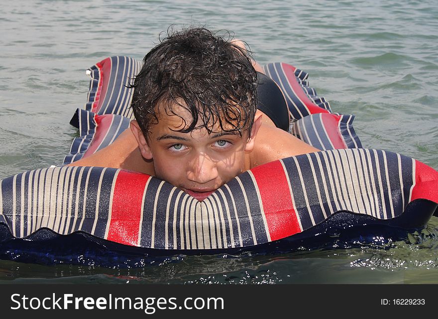 A young man enjoying the warm sun, floating on sea water. A young man enjoying the warm sun, floating on sea water