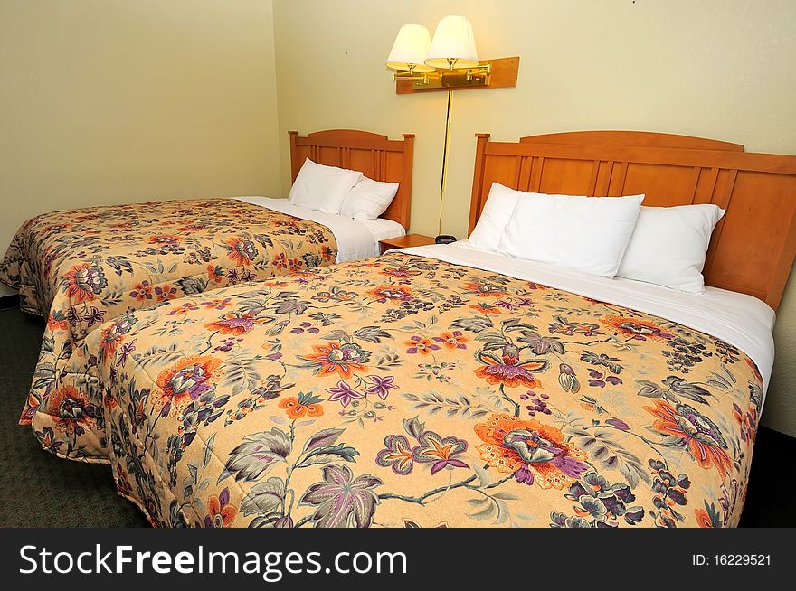 Double queen sized beds in generic hotel room. Suitable for concepts such as luxury, travel, tourism, vacation and holiday, and relaxation.