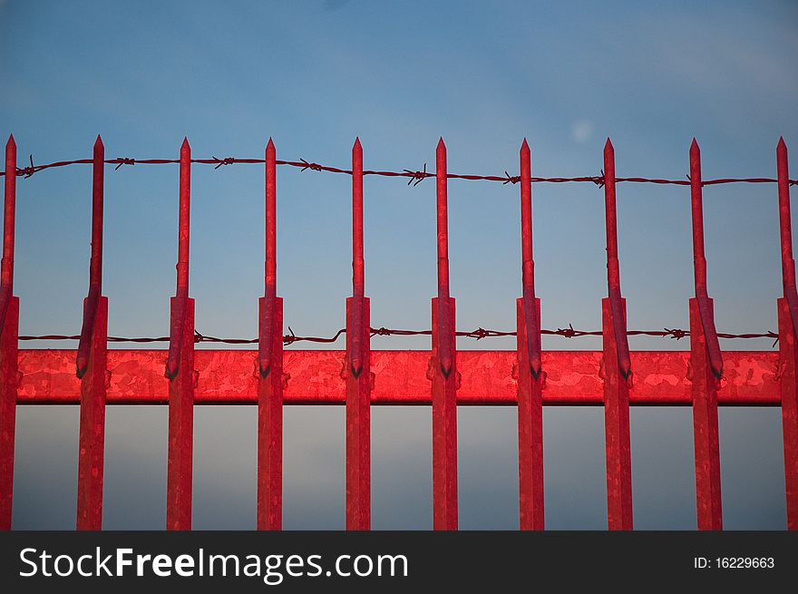 Red metal fence against blue sky