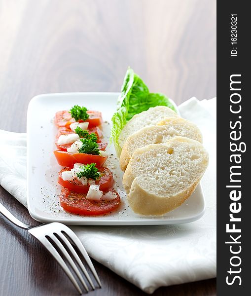 Tomato salad with baguette on plate