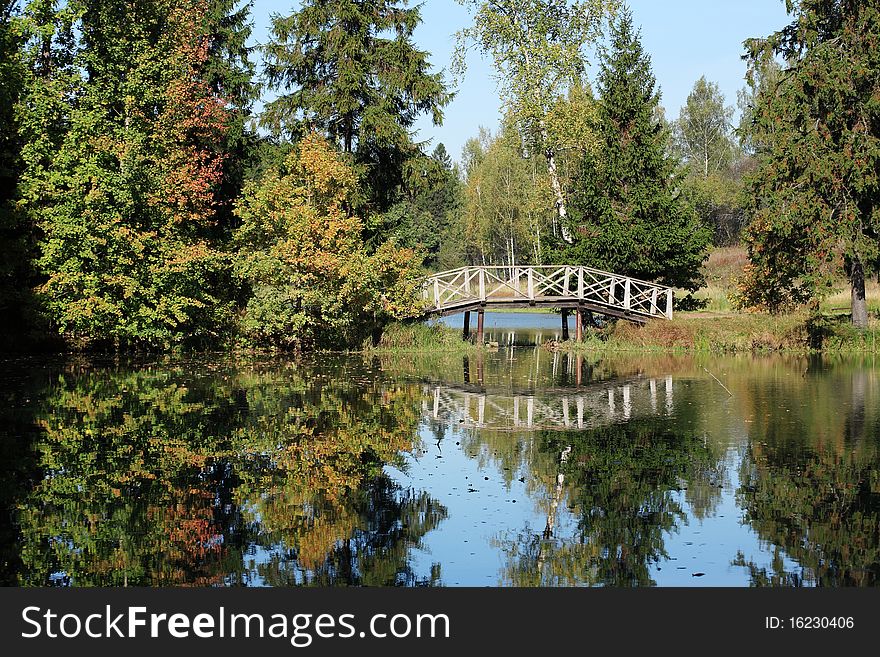 Autumn landscape with small wooden bridge across river