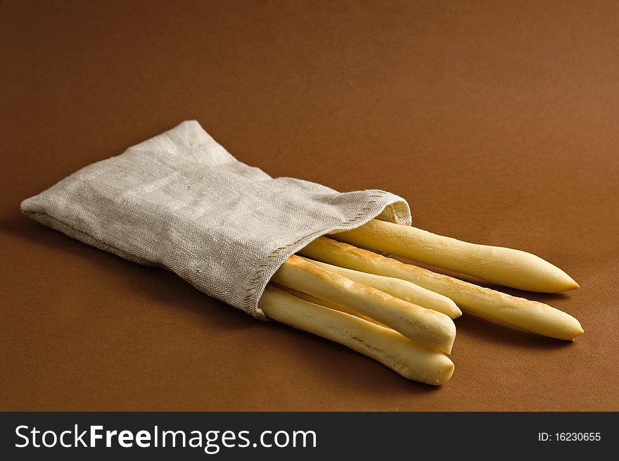 Bread sticks in sack on brown background