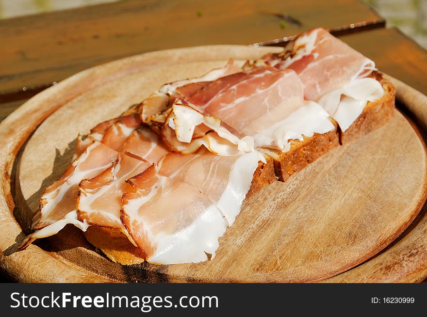Bread with bacon on a wooden plate