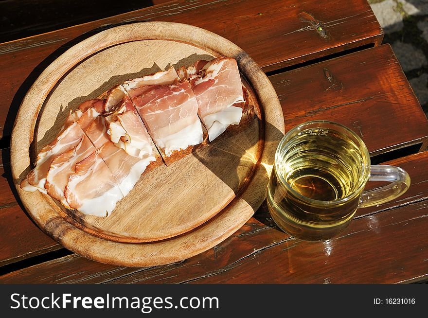 Bread with bacon on a wooden plate and a glass of apple juice. Bread with bacon on a wooden plate and a glass of apple juice