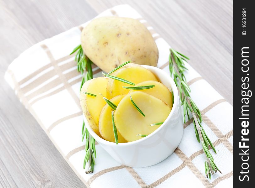 Potato in white bowl with rosemary. Potato in white bowl with rosemary