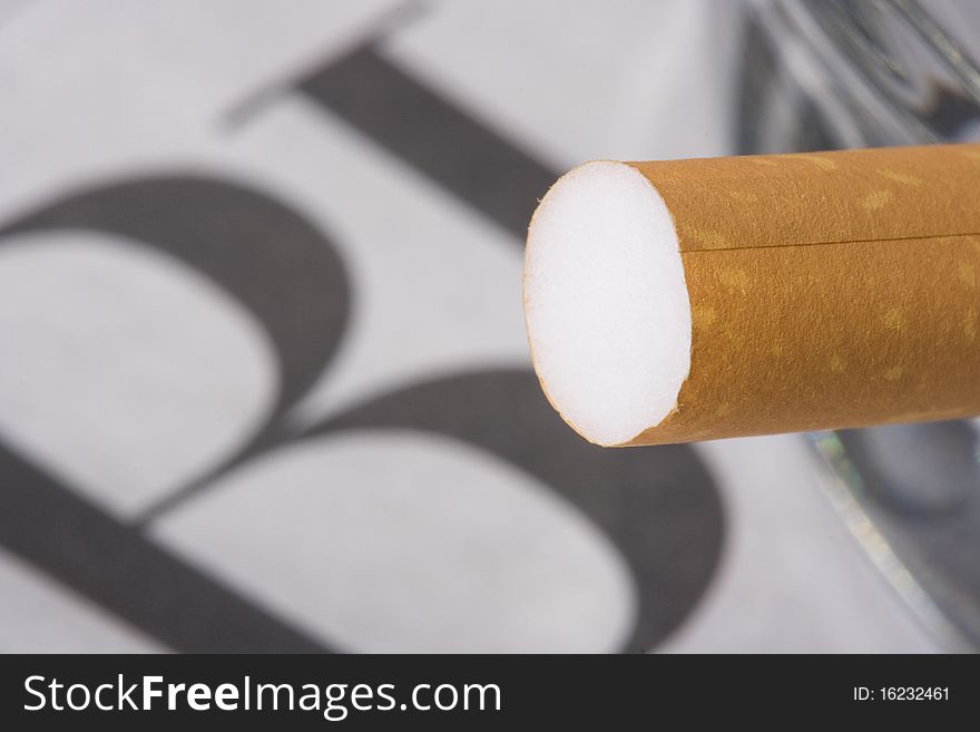 A cigarette filter in front of a newspaper with the word business on it.