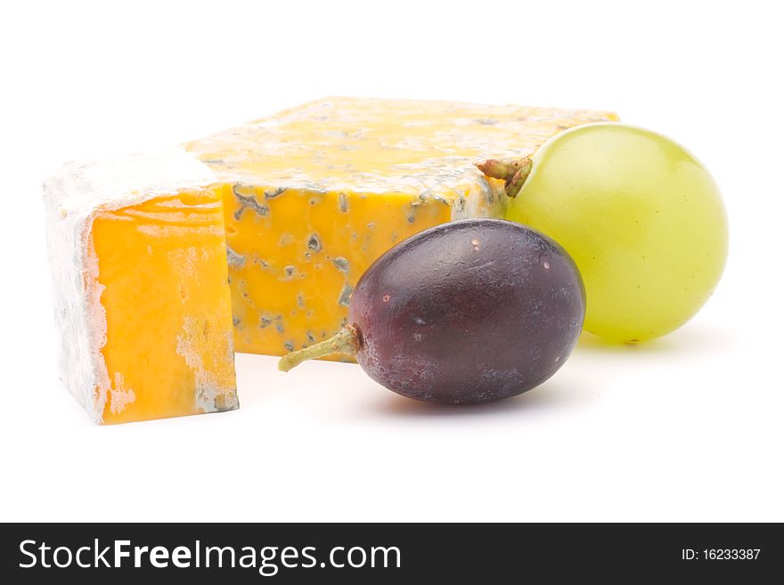 Cheese and a slice of cheese with mould and two grapes. Isolated on white background. Cheese and a slice of cheese with mould and two grapes. Isolated on white background