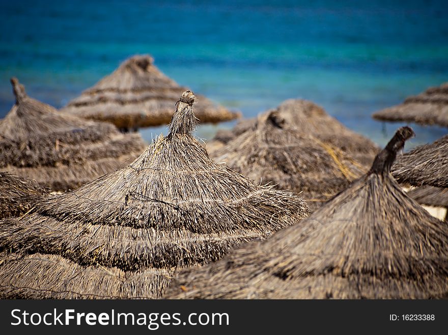 Straw roofs of umbrellas on a beach against the sea