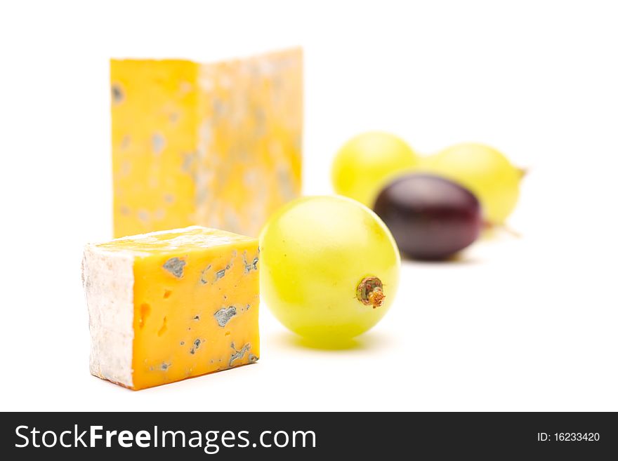 Cheese and a slice of cheese with mould and grapes. Isolated on white background. Cheese and a slice of cheese with mould and grapes. Isolated on white background