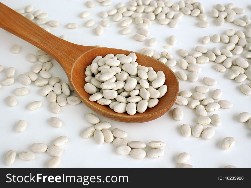Top view of wooden spoon full of white beans